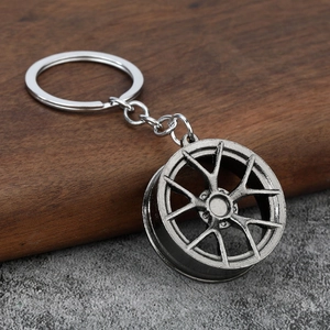 Close-up of a gun-grey metal car wheel hub keychain on a rustic wooden surface