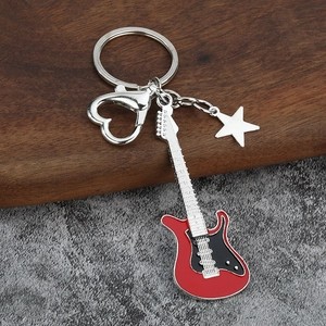 Detail of red electric guitar keychain with heart clasp and star charm on wood background