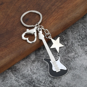 Close-up of guitar keychain with silver star charm and heart-shaped clasp on wood