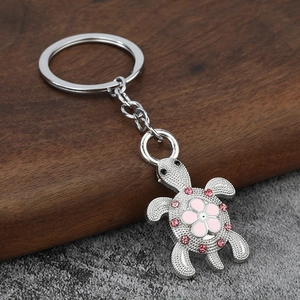 Macro detail of turtle keychain featuring a pink flower and sparkling rhinestones