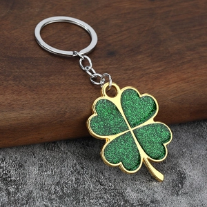 Macro detail of dark green clover keychain with glitter texture and gold metal edges