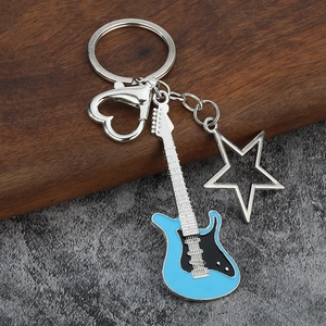 Detail of blue guitar keychain with heart and star charms on a stone surface