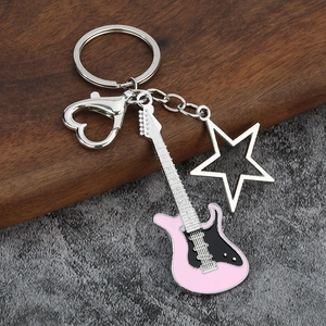 Detail of a pink electric guitar keychain with a hollow star pendant and heart clasp