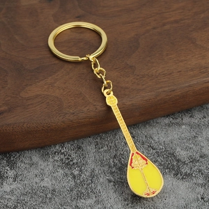 Golden Dombra instrument keychain with yellow enamel and red ethnic floral patterns