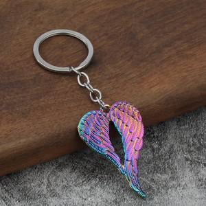 Macro detail of iridescent heart angel wing keychain on dark wood and grey stone surface