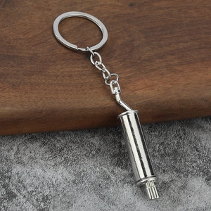 Polished silver car exhaust muffler keychain made of metal on industrial wooden desk