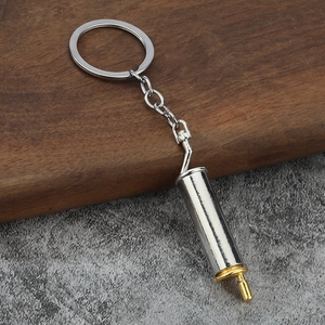 Close-up of a silver exhaust pipe keychain with gold plating on industrial background