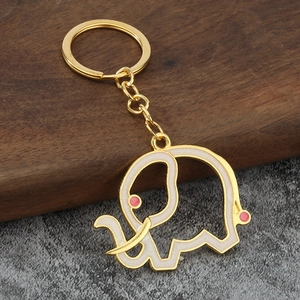 Close-up of golden elephant keychain with white enamel inlay and pink dot details