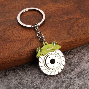 Macro detail of a green brake caliper and silver disc brake keychain with metallic finish