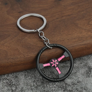 Dettaglio di un portachiavi a forma di volante da corsa con ruota nera e dettagli rosa
