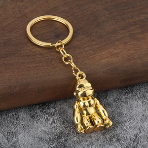 Golden gorilla shaped metal keychain with flat ring and polished finish on a wooden surface