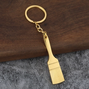 Detailed close-up of a creative gold shovel-shaped keychain with fine brush texture