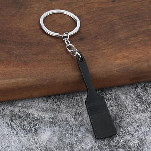 Detail view of a creative black shovel keychain with silver ring and fine textures
