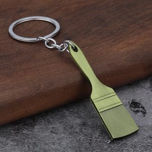 Creative green paint brush keychain made of textured alloy metal on a stone surface
