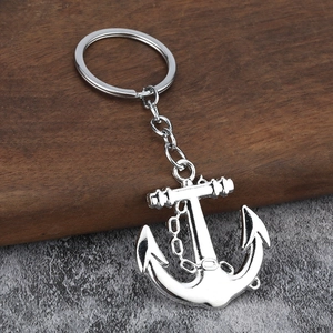Silver nautical anchor keychain with decorative chain on a rustic wooden surface