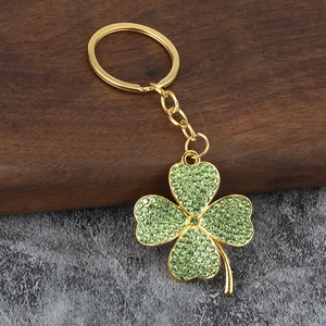 Golden lucky four leaf clover keychain with sparkling light green rhinestones on wood
