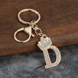 Détail du porte-clés doré lettre D avec couronne et cristaux blancs étincelants