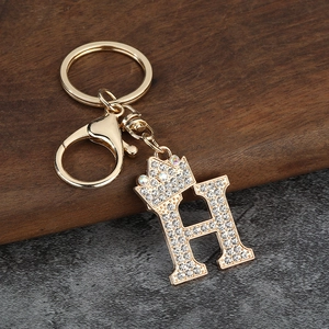 Détail macro du porte-clés lettre H doré avec couronne et strass étincelants incrustés