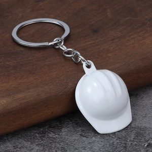 Creative white construction hard hat keychain with polished metal ring on wood surface