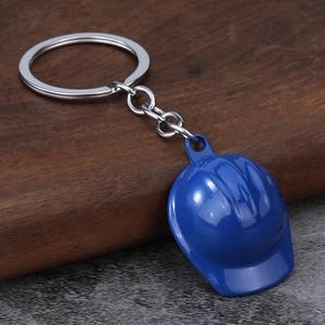 Detailed close-up of a blue mini safety helmet keychain on a dark wooden background