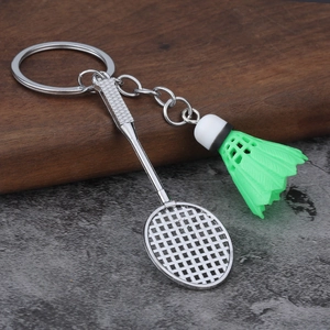 Macro view of a mini green shuttlecock and metal badminton racket sports keychain charm