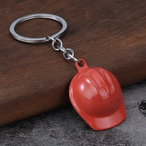 Macro shot of red safety helmet keychain with silver metal ring on a textured surface