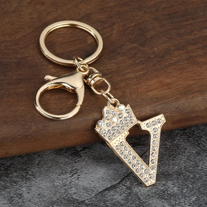 Détail du porte-clés couronne lettre V doré avec strass brillants et fermoir mousqueton