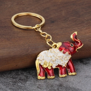 Creative elephant keychain with gold base and red enamel on a rustic stone background