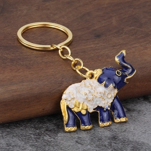 Creative blue and white enamel elephant keychain with gold metal frame on a stone surface