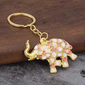 Detail of golden elephant keychain with colorful drip oil polka dots on walnut wood surface