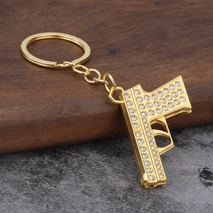 Macro detail of gold pistol keychain with sparkling rhinestones on textured wood