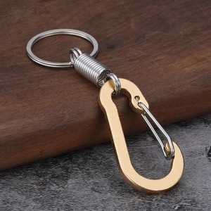 Close-up of golden D-ring carabiner and silver spring loop on a wooden surface
