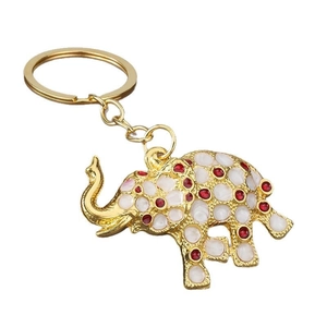 Golden elephant keychain with white enamel inlay and vibrant red rhinestone accents