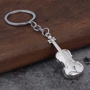 Detailed close-up of a vintage silver-colored violin metal keychain on a wood surface