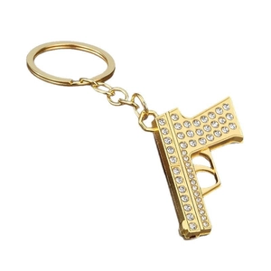 Hip hop style gold pistol keychain with sparkling rhinestones on a white background