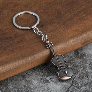 Detailed close-up of a vintage bronze violin keychain on a rustic wooden surface