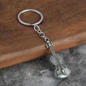 Macro detail of a vintage silver violin keychain on a rustic wooden and stone surface