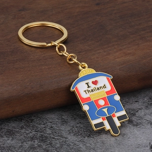 Close-up of golden Thai Tuk Tuk taxi keychain on rustic wooden and gray textured surface