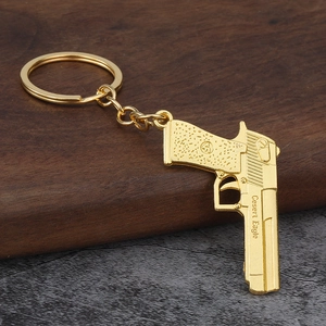 Golden Desert Eagle metal pistol keychain model on wooden block with metal ring