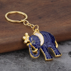 Macro view of blue enamel Thai elephant keychain with gold crown on wood surface