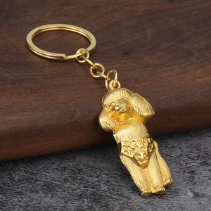 Close-up of golden poodle keychain with brushed metal texture on rustic wood background