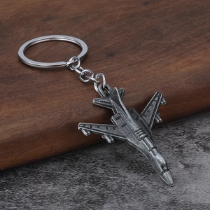 Detailed close-up of a vintage silver fighter jet metal keychain on a rustic surface