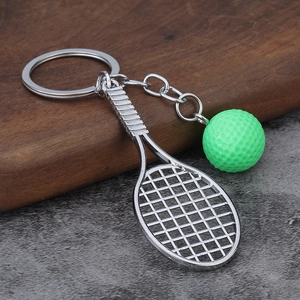 Close-up of mini tennis racket keychain with realistic neon green ball on wood base