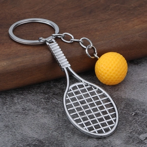 Macro detail of a silver tennis racket and yellow felt ball keychain pendant
