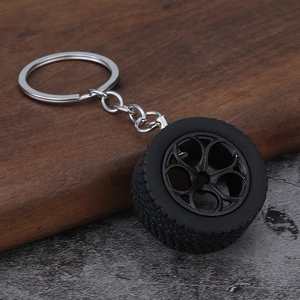 Close-up of car tire keychain with five-spoke wheel hub on walnut wood background