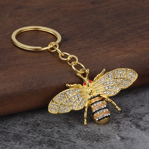Sparkling gold honey bee keychain with crystals and enamel stripes on dark wood