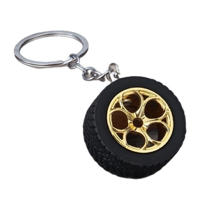 Car tire keychain with golden wheel rim and black rubber tire on white background
