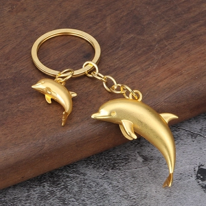 Prachtige gouden dubbele dolfijn sleutelhanger met matte legering op houten ondergrond