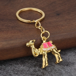 Exquisite golden camel keychain with pink enamel detail on dark textured background
