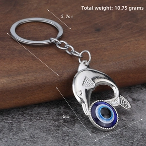 Detail of silver dolphin keychain with blue evil eye amulet on textured stone background